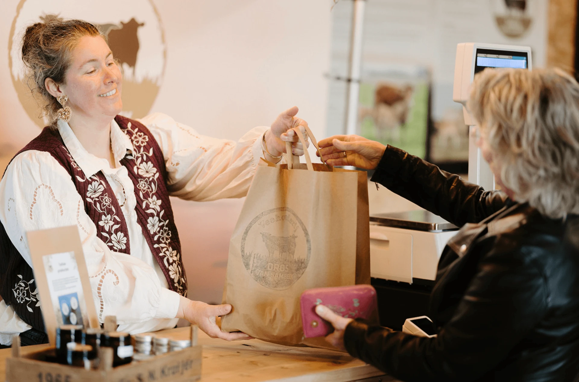 Kim helpt een klant aan de toonbank van de boerderijwinkel